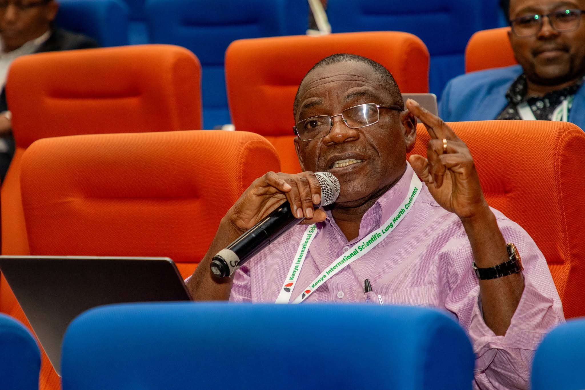 A delegate raises a question from the audience during a symposium session