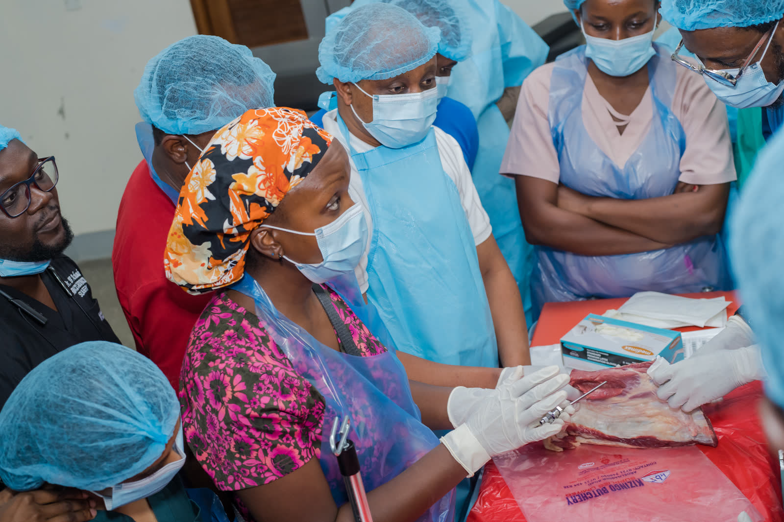 Participants in caps and aprons practising a pleural procedure during a hands-on session