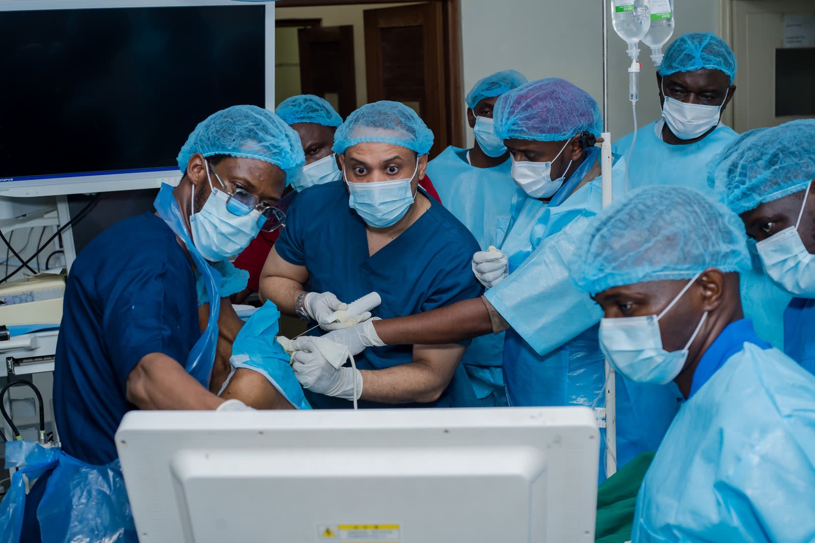 Faculty and participants gather around the ultrasound screen during a live procedure